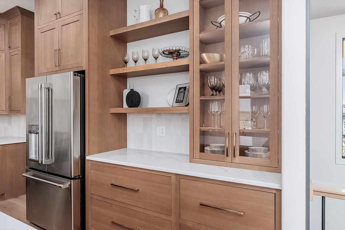Light brown stained cabinets with floating shelves and glass doors on a countertop cabinet