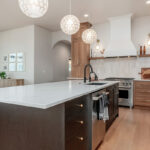 Light brown-stained kitchen cabinets with a white painted wood hood and dark stained island cabinets