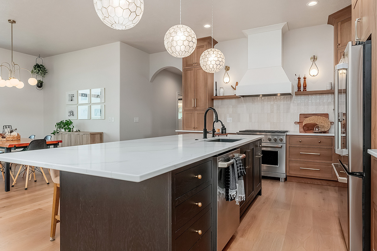 Light brown-stained kitchen cabinets with a white painted wood hood and dark stained island cabinets