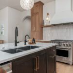Light brown-stained kitchen cabinets with a white painted wood hood and dark stained island cabinets