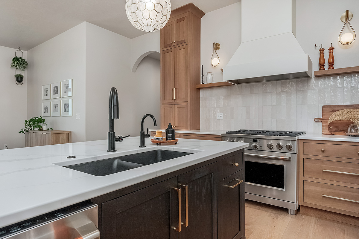 Light brown-stained kitchen cabinets with a white painted wood hood and dark stained island cabinets