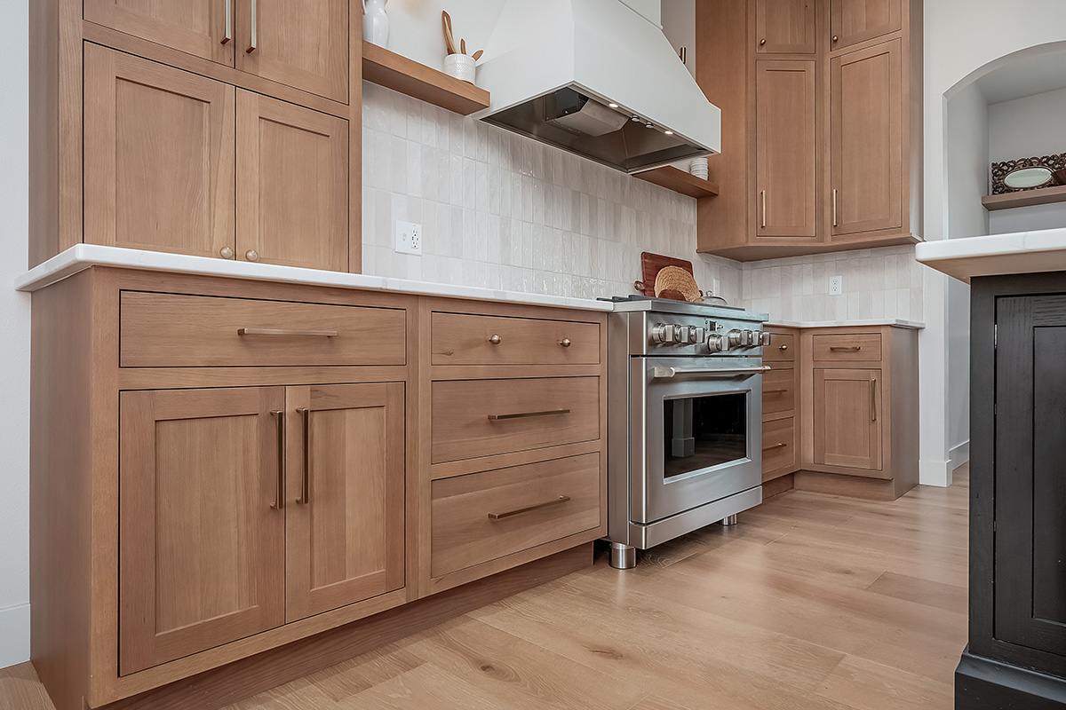 Light brown-stained kitchen cabinets with a white painted wood hood