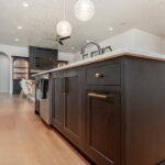 Dark stained island cabinets with living room and fireplace shown in the distance