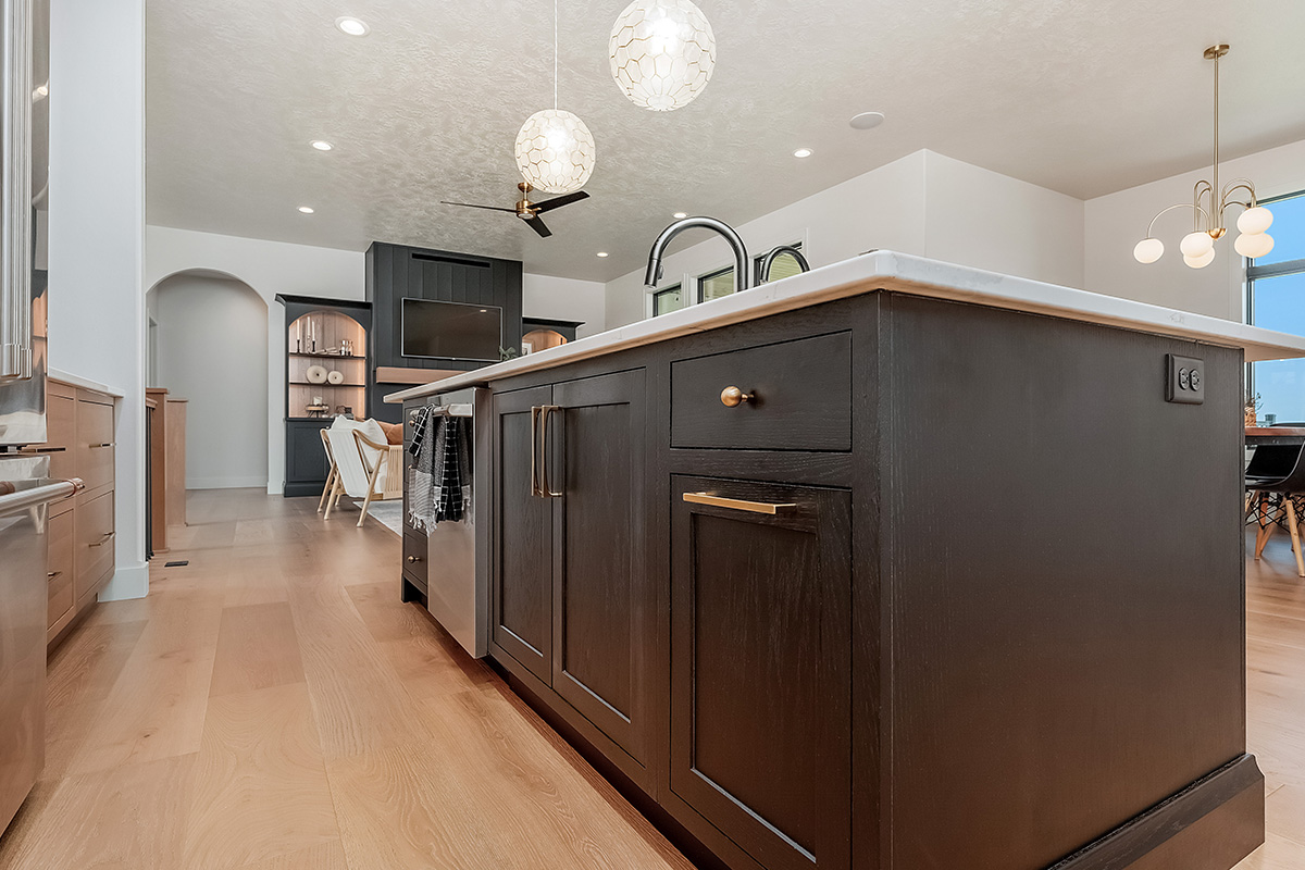 Dark stained island cabinets with living room and fireplace shown in the distance