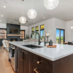 Dark stained island cabinets with living room and fireplace shown in the distance