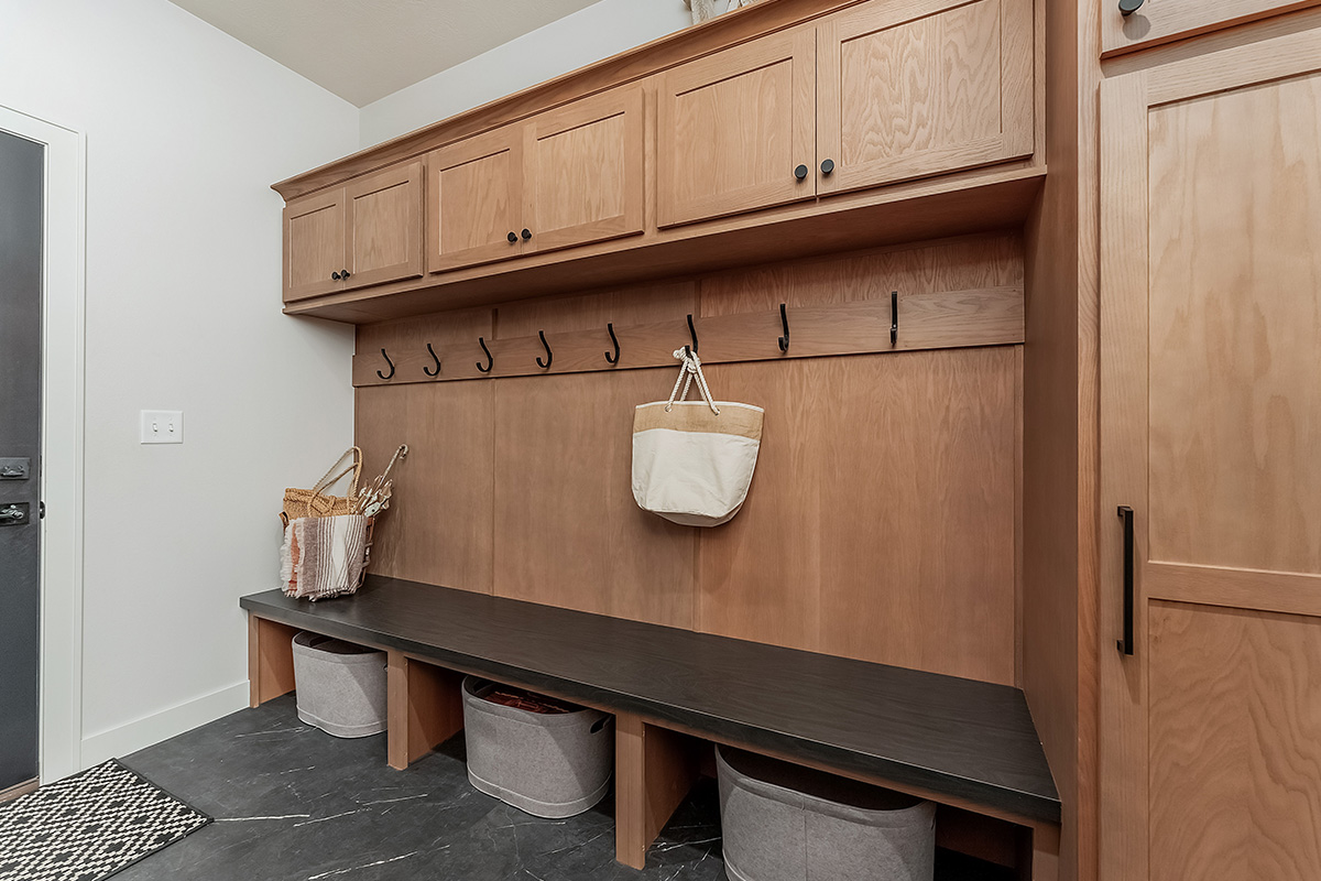 Light brown stained mudroom locker cabinets with dark stained bench seating