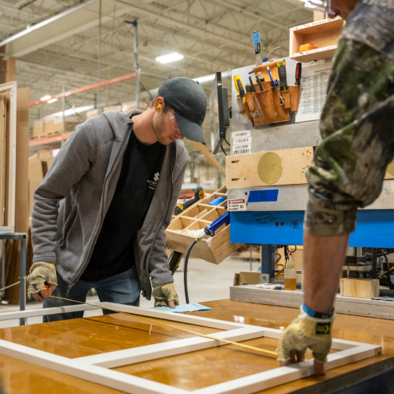 Man measuring a cabinet frame before beginning to build a cabinet