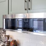 Painted green kitchen cabinets with unique wallpaper showing close up of microwave