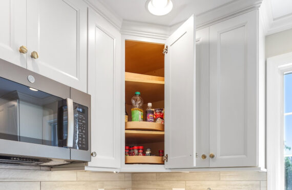 White painted Diagonal Wall Wood Susan cabinet with door open.
