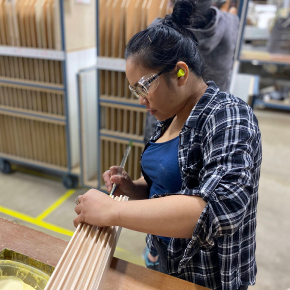 Woman applying glue to cabinet door parts