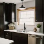 Black painted kitchen cabinets. View of kitchen sink with window above.