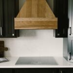 Black painted kitchen cabinets with light brown stained hood and island