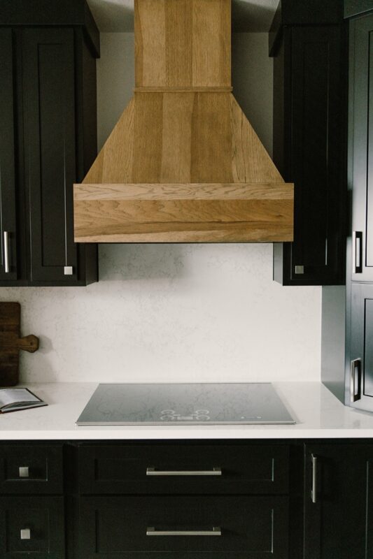 Black painted kitchen cabinets with light brown stained hood and island
