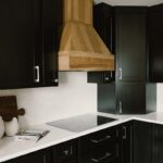 Black painted kitchen cabinets with light brown stained hood and island