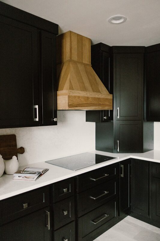 Black painted kitchen cabinets with light brown stained hood and island