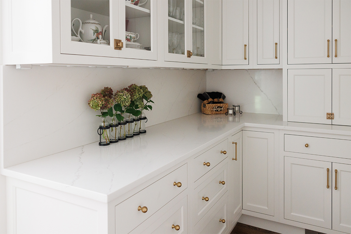 White kitchen with glass doors on two cabinets showing dishware.