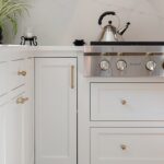 White kitchen. View of range below hood with a pot faucet.