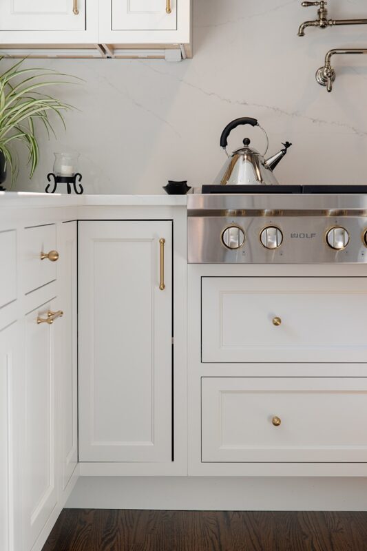 White kitchen. View of range below hood with a pot faucet.