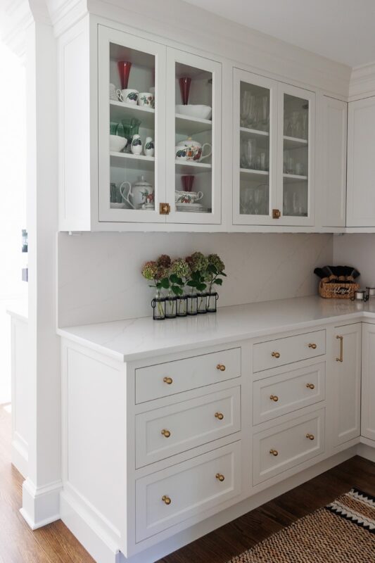 White kitchen with glass doors on two cabinets showing dishware.