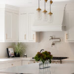 White kitchen. View of range below hood with a pot faucet.