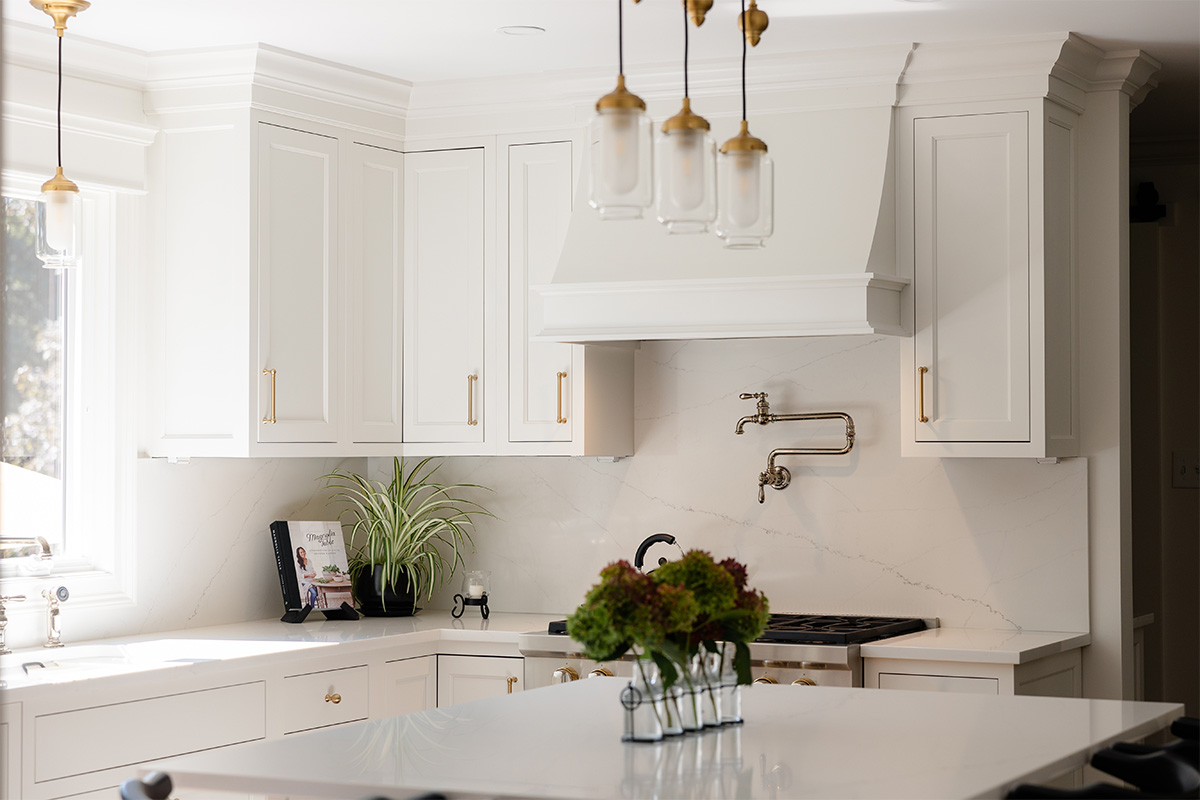 White kitchen. View of range below hood with a pot faucet.