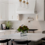 White kitchen. View of range below hood with a pot faucet.