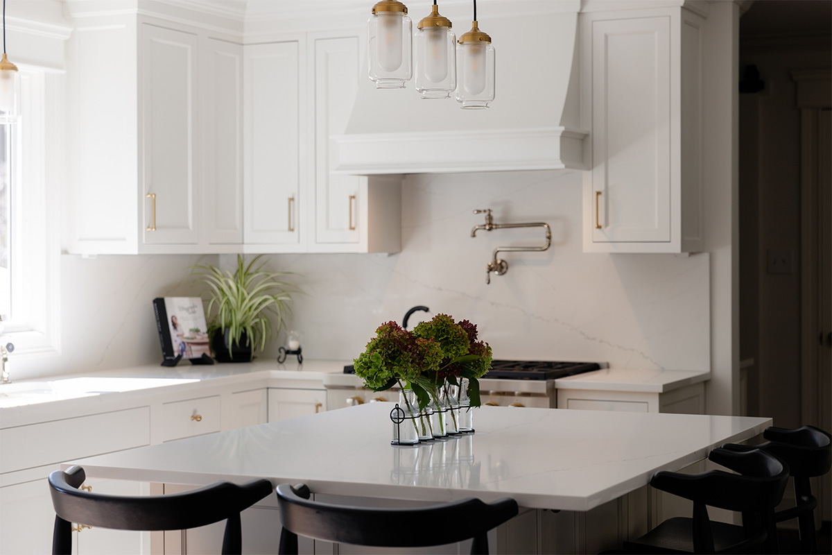 White kitchen. View of range below hood with a pot faucet.