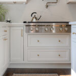 White kitchen. View of range below hood with a pot faucet.