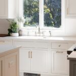 White kitchen cabinets with view of sink and window.