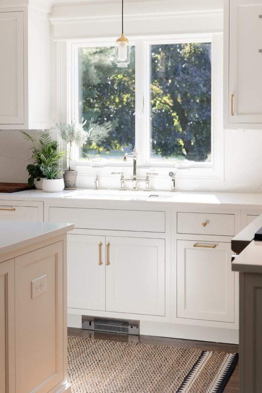 White kitchen cabinets with view of sink and window.