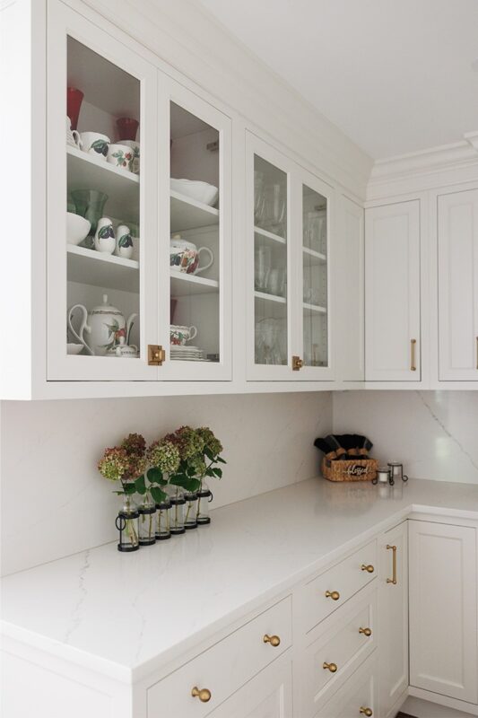 White kitchen with glass doors on two cabinets showing dishware.