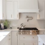White kitchen. View of range below hood with a pot faucet.