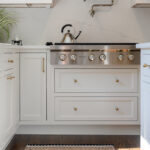 White kitchen. View of range below hood with a pot faucet.