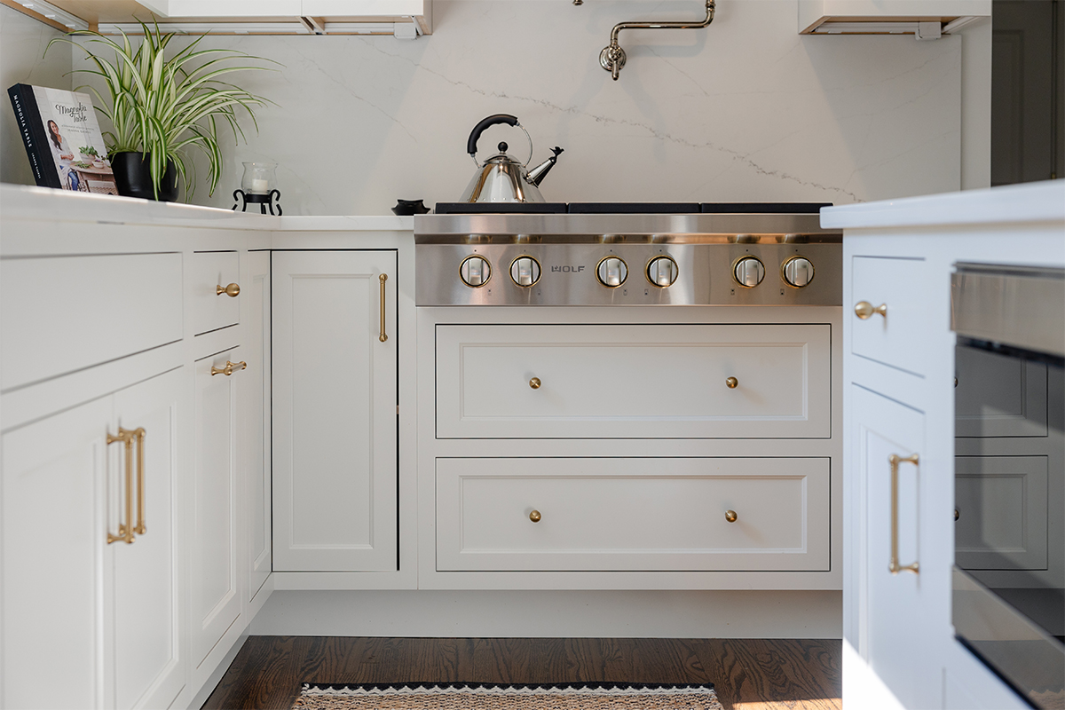 White kitchen. View of range below hood with a pot faucet.