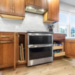 Stained kitchen cabinets with stove and cabinets with open doors showing interior storage on each side