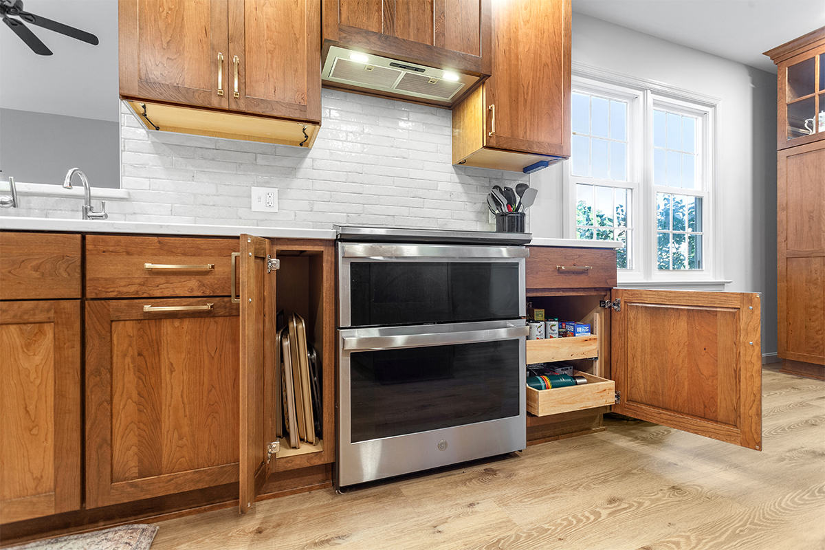 Stained kitchen cabinets with stove and cabinets with open doors showing interior storage on each side
