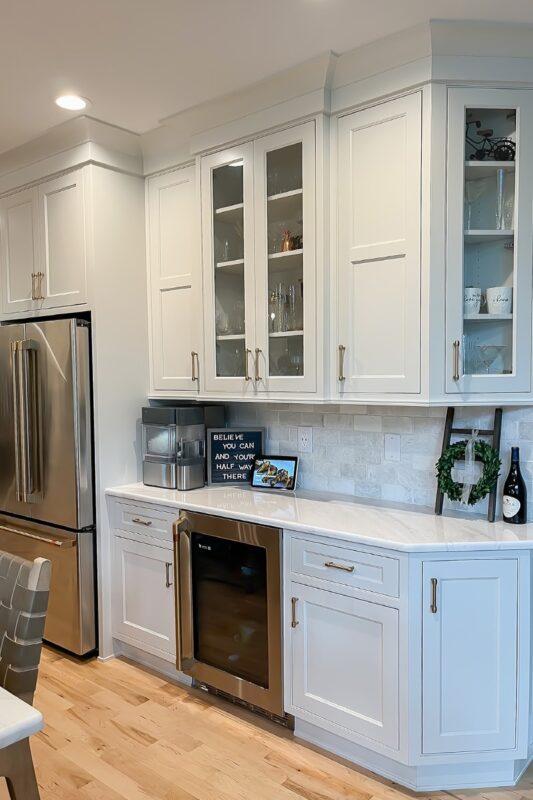 White painted cabinets with stainless steel appliances and wall cabinet with glass doors