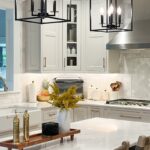 White painted kitchen with metal lights over island.