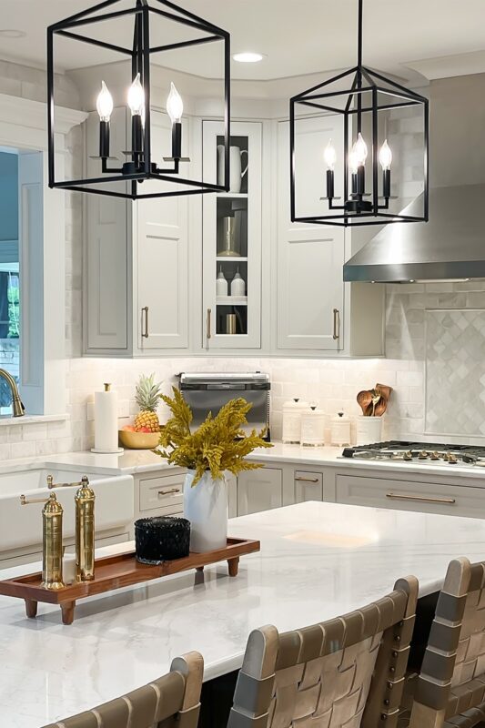 White painted kitchen with metal lights over island.