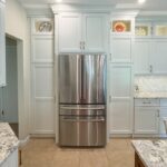 White painted kitchen cabinets and stainless-steel fridge.