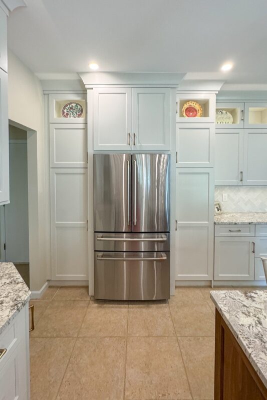 White painted kitchen cabinets and stainless-steel fridge.
