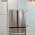White painted kitchen cabinets and stainless-steel fridge.