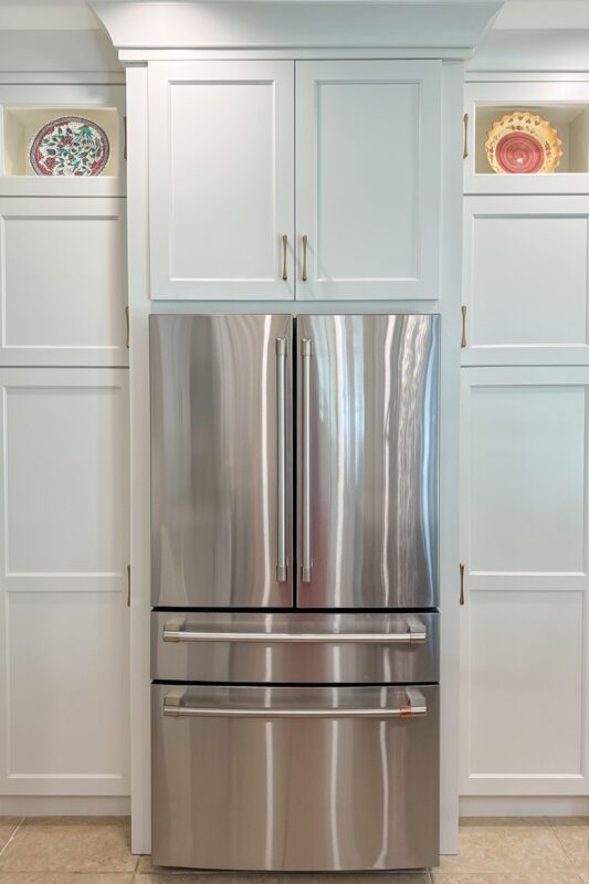 White painted kitchen cabinets and stainless-steel fridge.