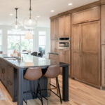 Kitchen with light brown stained perimeter cabinets and dark stained island.