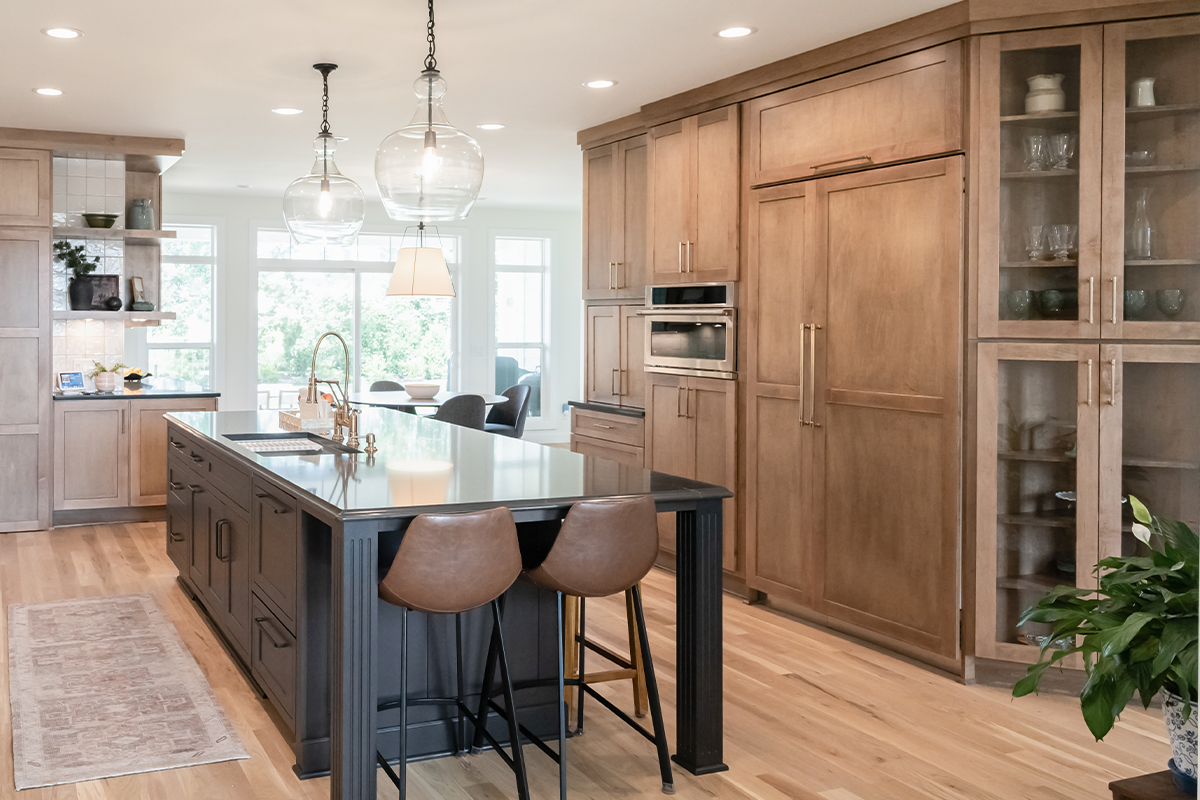 Kitchen with light brown stained perimeter cabinets and dark stained island.