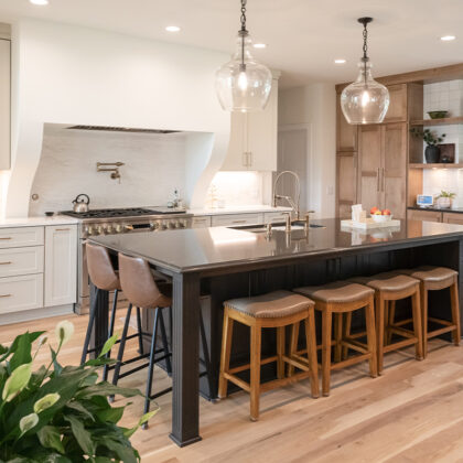 Kitchen with light brown stained and white painted perimeter cabinets and dark stained island.