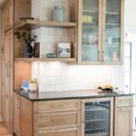 Stained kitchen cabinets with open shelves, glass door upper cabinet and beverage cooler below.