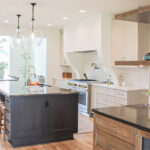 Kitchen view of dark stained island, white painted perimeter and light brown stained accent cabinets.