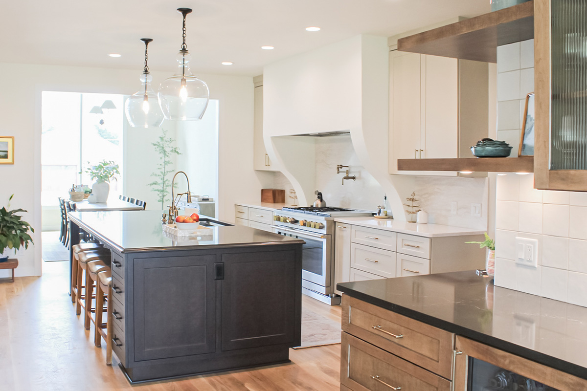 Kitchen view of dark stained island, white painted perimeter and light brown stained accent cabinets.