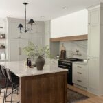 Small painted kitchen. Cabinets in light gray paint. Box hood painted white with stained brown accent that matches the stained island.